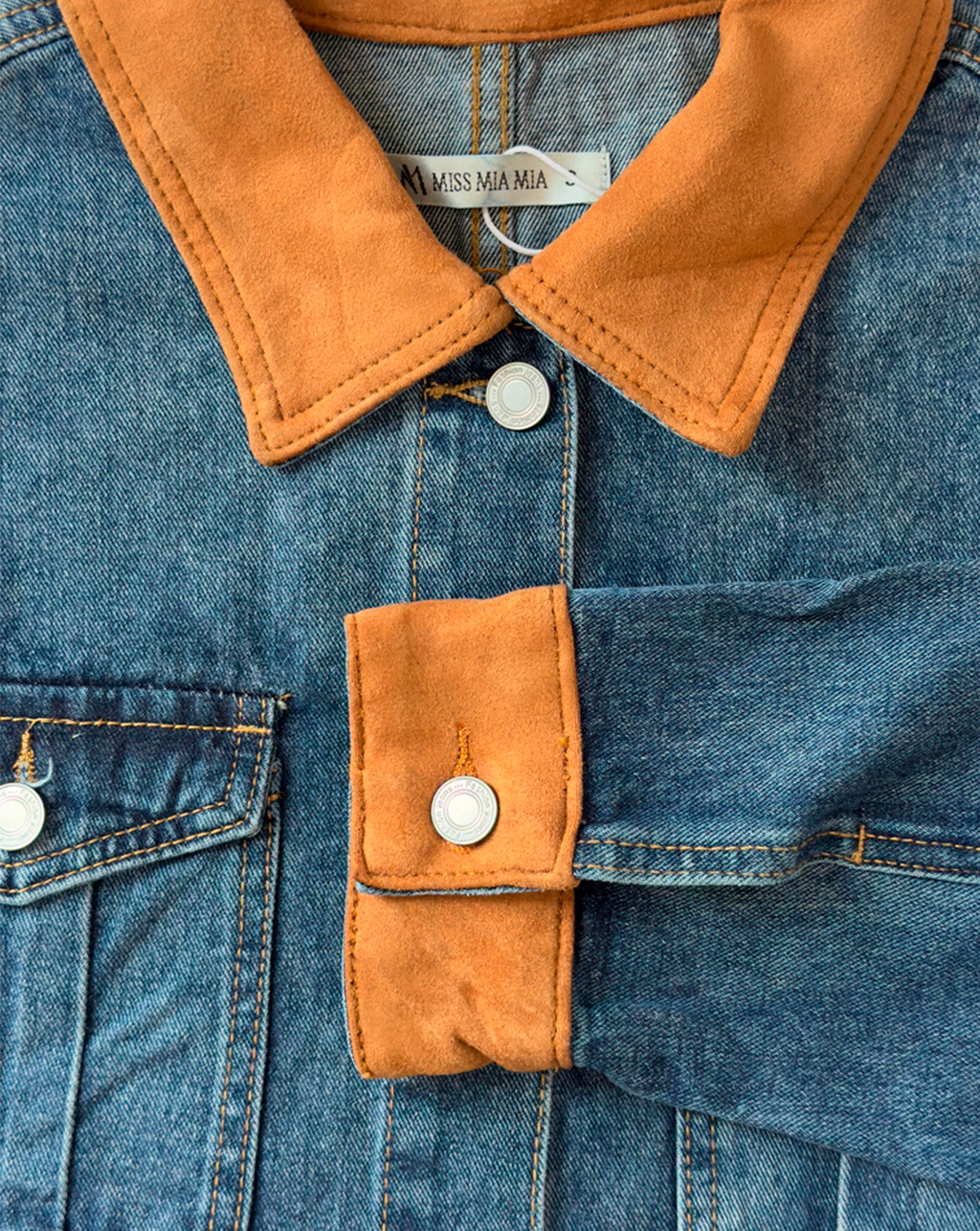 Detalle de chaqueta de mezclilla azul en cuello y mangas, estilo casual femenino